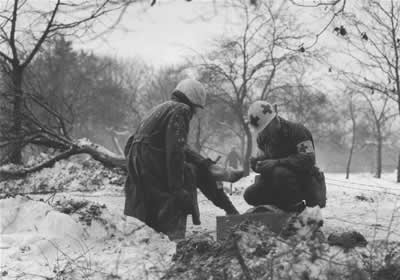 Caring for an infantryman injured in the Ardennes fighting.