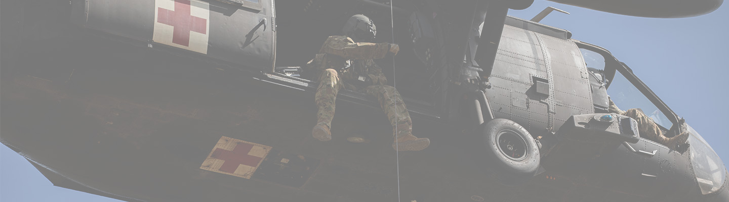 A US Army soldier guiding a hoist cable from a medical evacuation helicopter during a training exercise.